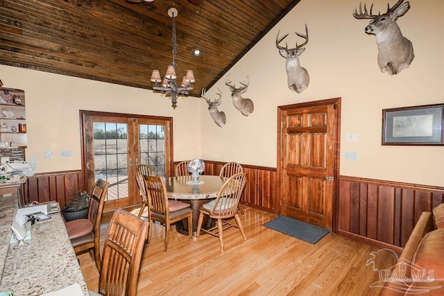 dining area with a chandelier, wood ceiling, vaulted ceiling, light wood-type flooring, and wainscoting