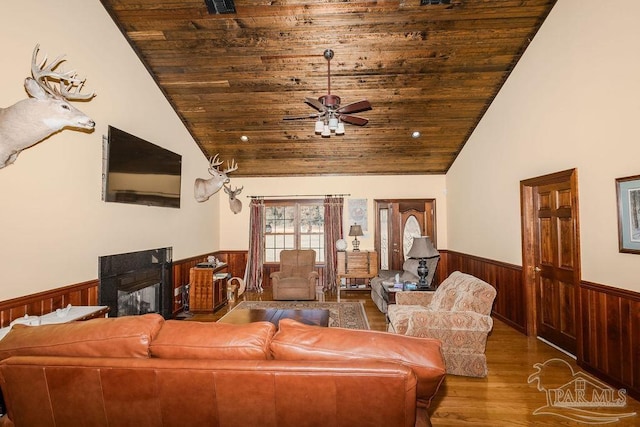 living room with lofted ceiling, wainscoting, a fireplace, and wooden ceiling