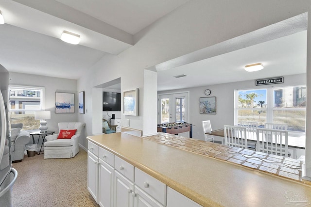 kitchen with white cabinets, french doors, stainless steel refrigerator, and a wealth of natural light