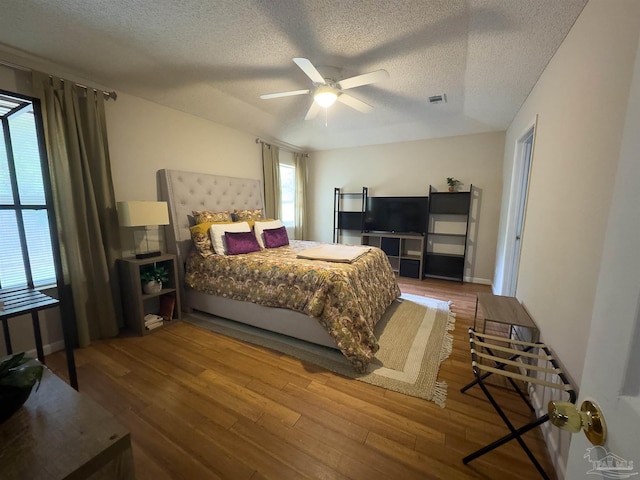 bedroom with visible vents, a ceiling fan, a textured ceiling, and wood finished floors
