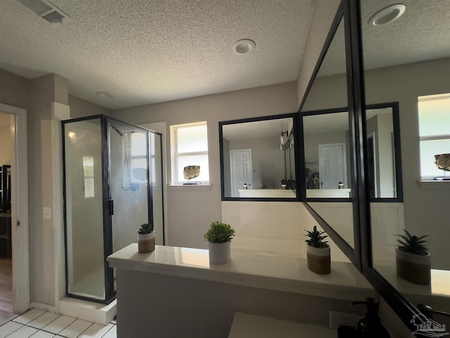 bathroom featuring plenty of natural light, a stall shower, and a textured ceiling