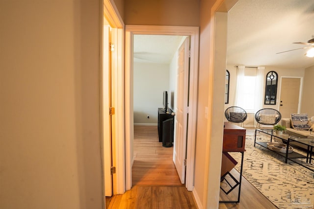 corridor with light wood-style floors and baseboards