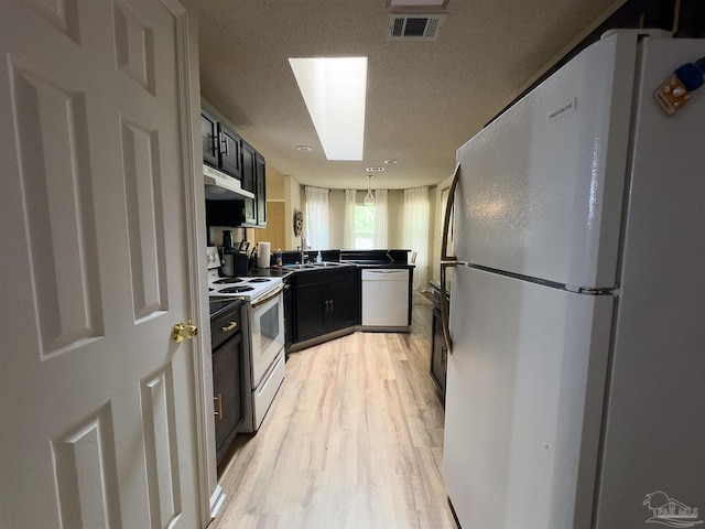 kitchen featuring visible vents, white appliances, light wood-type flooring, dark cabinetry, and a sink