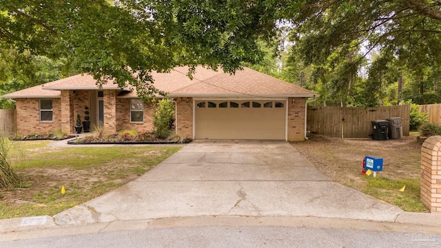 ranch-style home featuring a garage, fence, roof with shingles, brick siding, and driveway