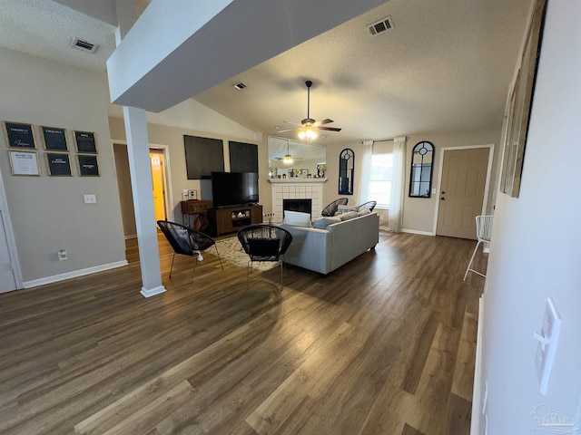 living area featuring dark wood finished floors, a ceiling fan, baseboards, a tile fireplace, and visible vents