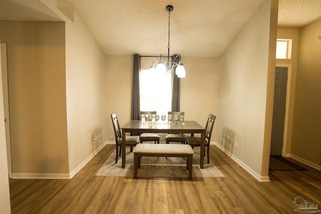 dining space with baseboards, a textured ceiling, wood finished floors, and a chandelier