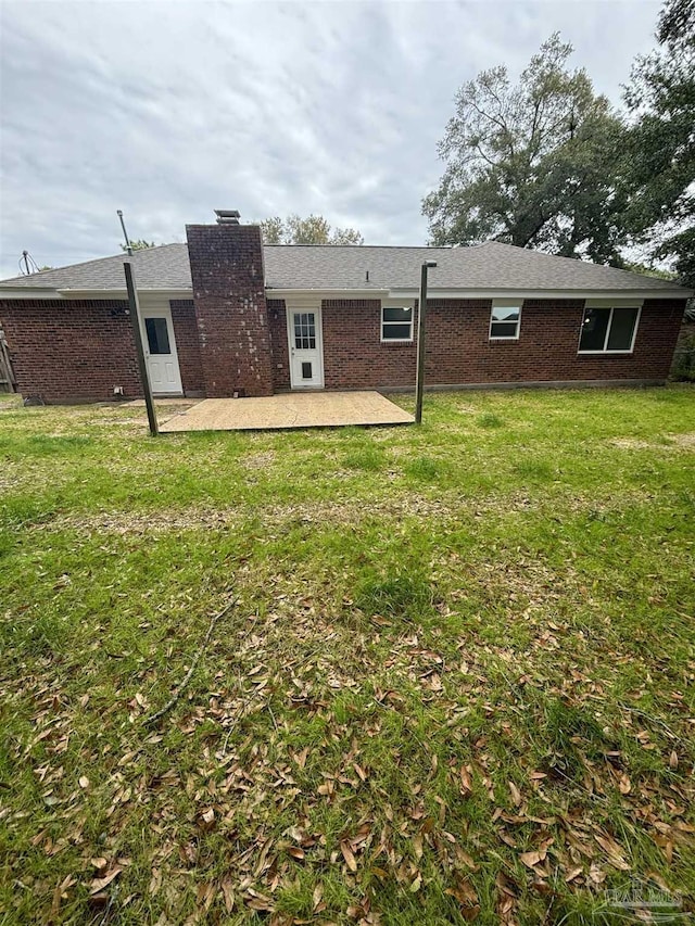 back of property featuring a patio area and a lawn