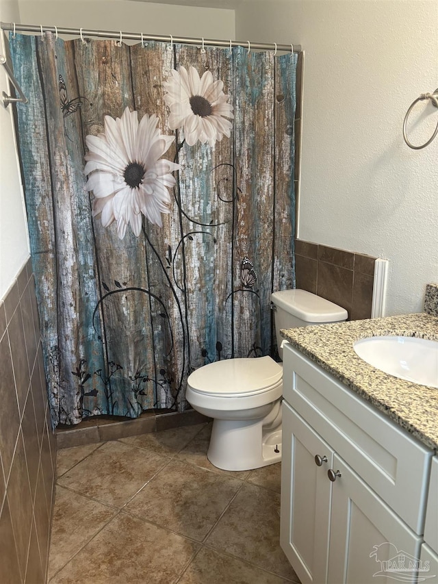 bathroom featuring vanity, toilet, tile patterned flooring, and tile walls