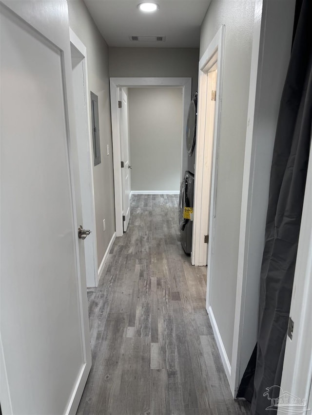 hallway with dark hardwood / wood-style flooring and stacked washing maching and dryer