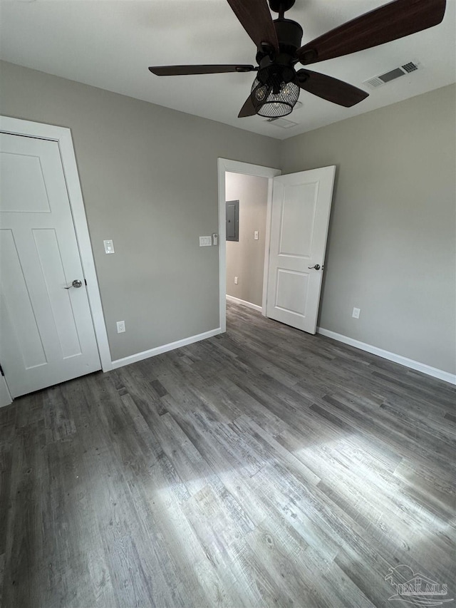 empty room featuring dark hardwood / wood-style floors, electric panel, and ceiling fan