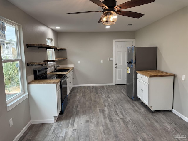 kitchen with sink, stainless steel refrigerator, butcher block counters, electric range oven, and white cabinets