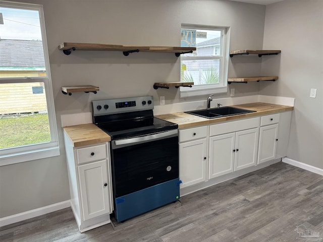 kitchen featuring butcher block countertops, sink, light hardwood / wood-style flooring, white cabinets, and stainless steel electric range oven