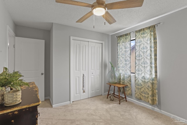 bedroom with a textured ceiling, baseboards, carpet, a closet, and ceiling fan