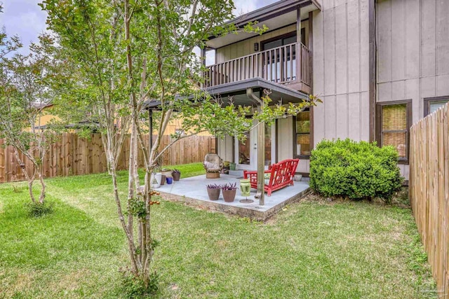 view of yard with a patio area, a fenced backyard, and a balcony