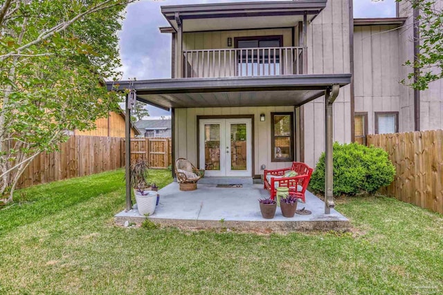 rear view of house featuring a fenced backyard, french doors, a balcony, and a yard