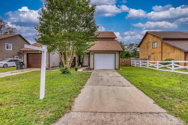 view of front of property featuring a front lawn, driveway, fence, and a garage