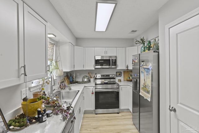 kitchen with light wood-style floors, light countertops, white cabinets, appliances with stainless steel finishes, and visible vents