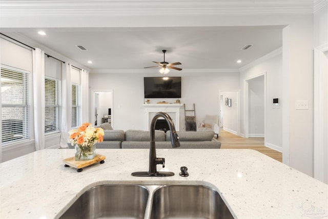 9938 Suwanee Ln, Pensacola, FL 32526 - kitchen with a sink, a fireplace, light stone counters, light wood-style floors, and ceiling fan