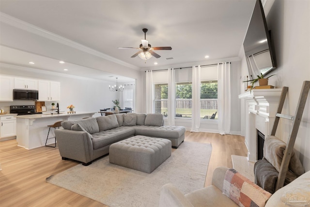 9938 Suwanee Ln, Pensacola, FL 32526 - living room featuring light wood-style floors, a ceiling fan, a fireplace, ornamental molding, and a chandelier