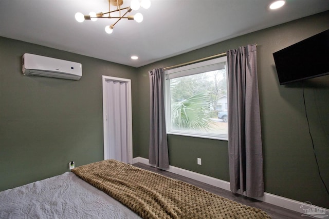 bedroom with hardwood / wood-style flooring, a wall mounted air conditioner, and a notable chandelier