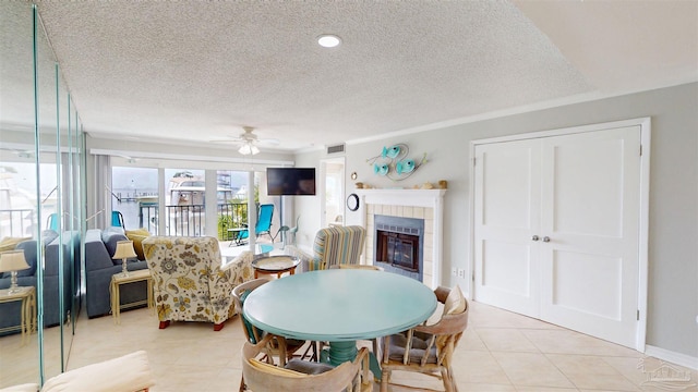 dining room with light tile patterned floors, visible vents, a tiled fireplace, and a ceiling fan