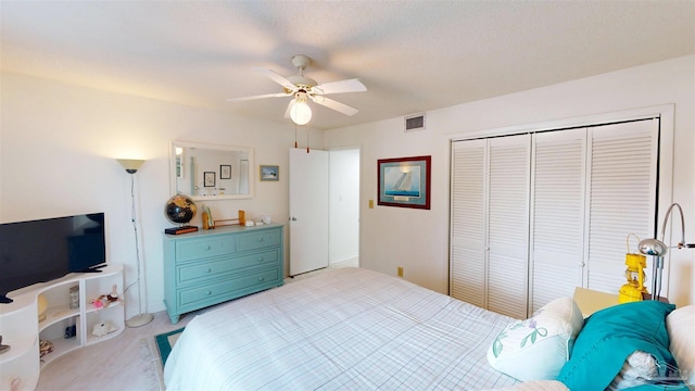 bedroom featuring a closet, light carpet, a textured ceiling, visible vents, and ceiling fan