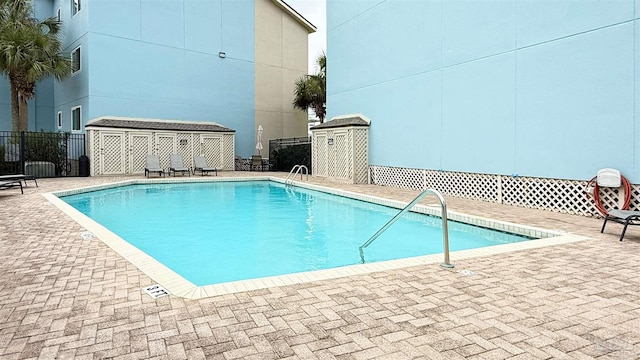 pool featuring a patio, an outbuilding, fence, and a shed