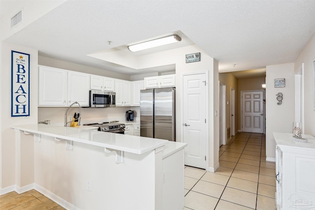 kitchen with a breakfast bar area, appliances with stainless steel finishes, kitchen peninsula, and white cabinets