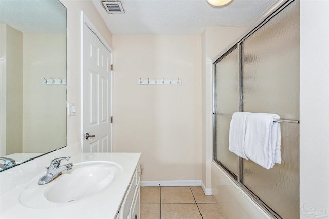 bathroom with tile patterned floors, shower / bath combination with glass door, a textured ceiling, and vanity