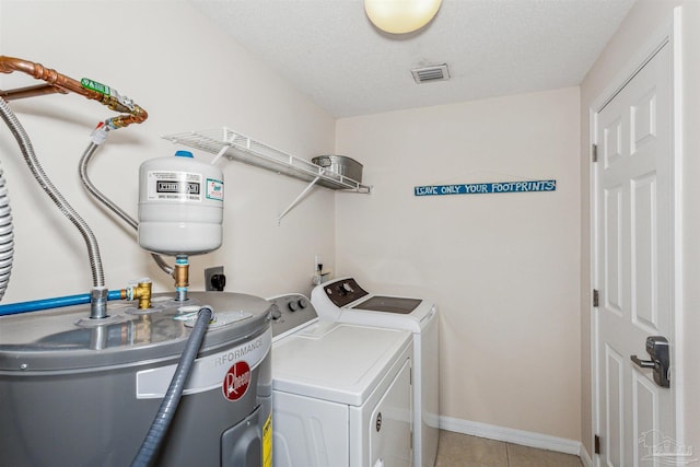 clothes washing area featuring a textured ceiling, independent washer and dryer, light tile patterned floors, and water heater