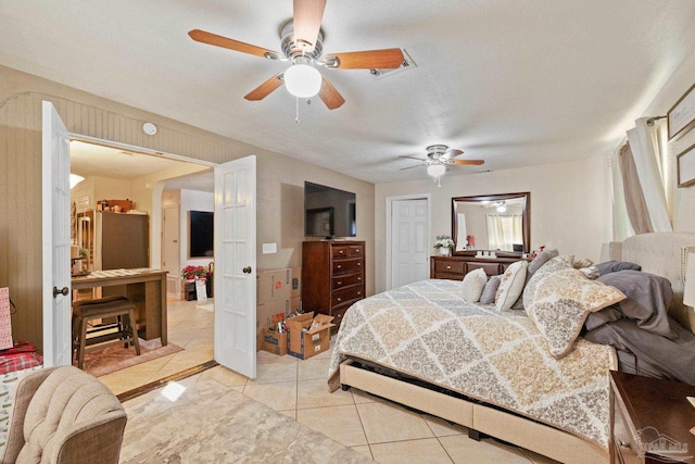 bedroom with stainless steel refrigerator, ceiling fan, light tile patterned floors, and a textured ceiling