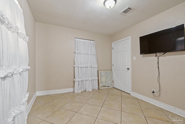 tiled empty room with a textured ceiling