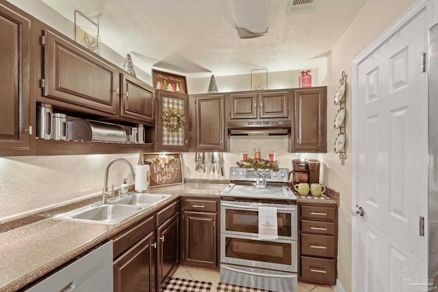 kitchen with light tile patterned floors, dark brown cabinetry, stainless steel appliances, and sink