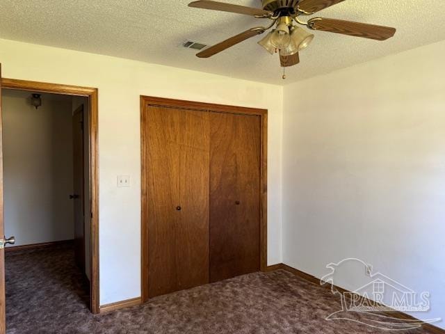 unfurnished bedroom featuring ceiling fan, a closet, dark carpet, and a textured ceiling