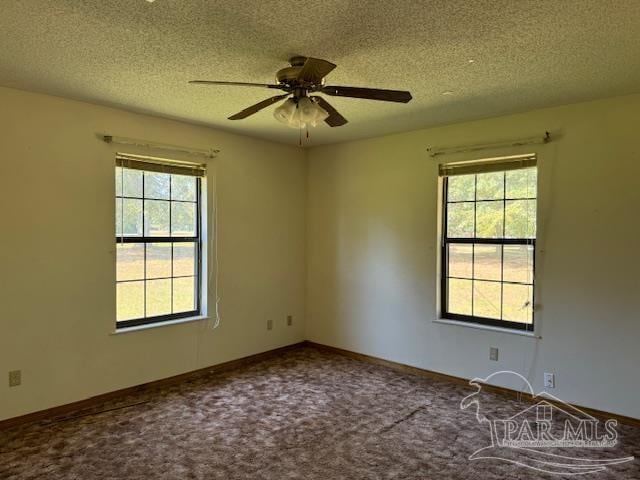 carpeted empty room with ceiling fan, plenty of natural light, and a textured ceiling