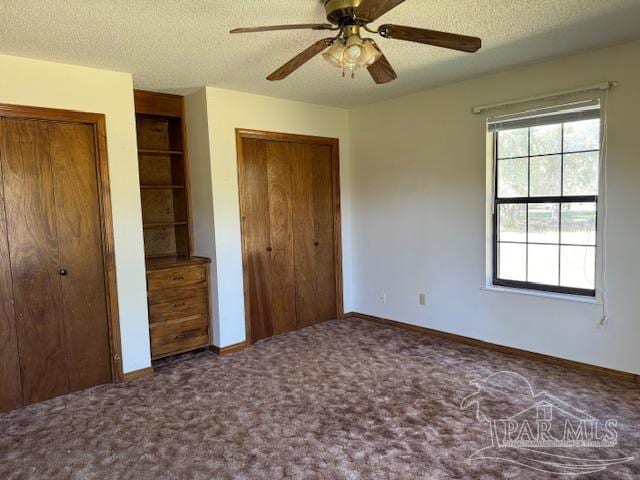 unfurnished bedroom featuring a textured ceiling, carpet floors, ceiling fan, and multiple closets