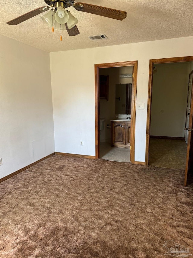 interior space featuring a textured ceiling, dark carpet, and ceiling fan