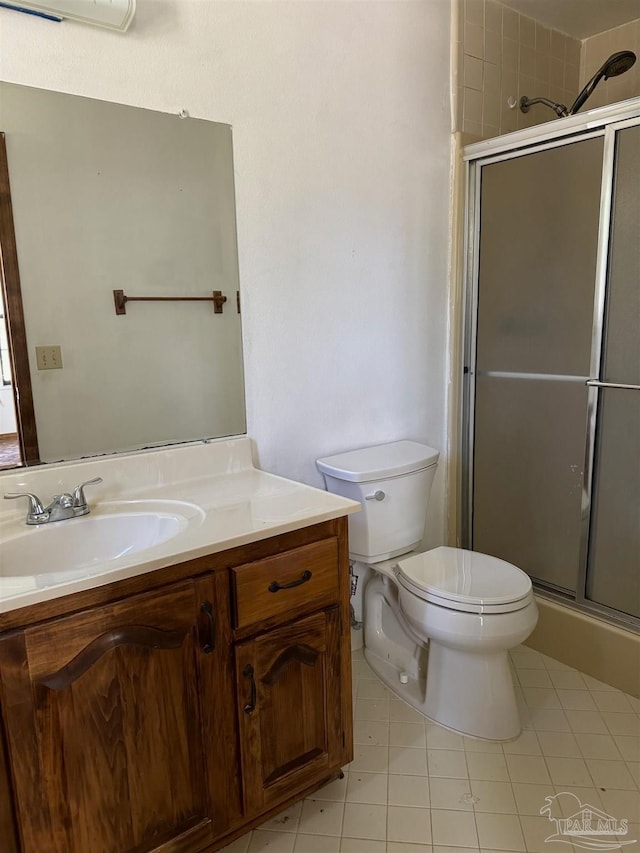 bathroom featuring tile patterned floors, vanity, an enclosed shower, and toilet