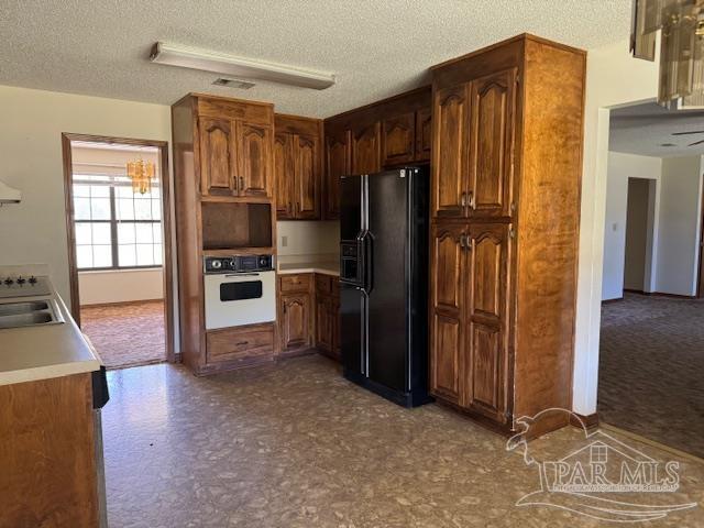 kitchen featuring black fridge with ice dispenser, white oven, a textured ceiling, and exhaust hood