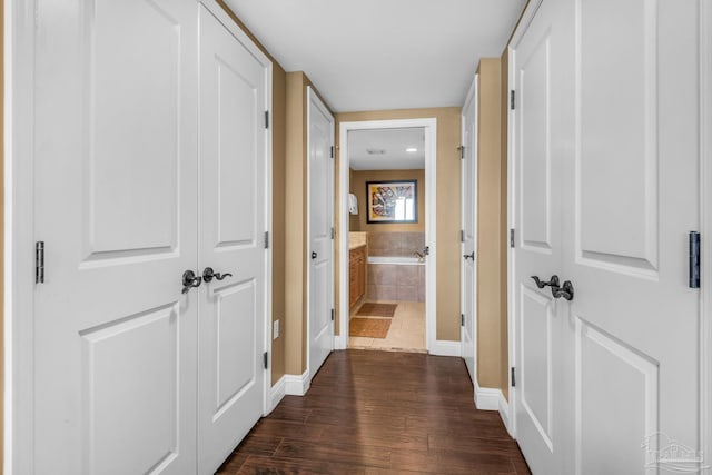 hall featuring baseboards and dark wood-style flooring