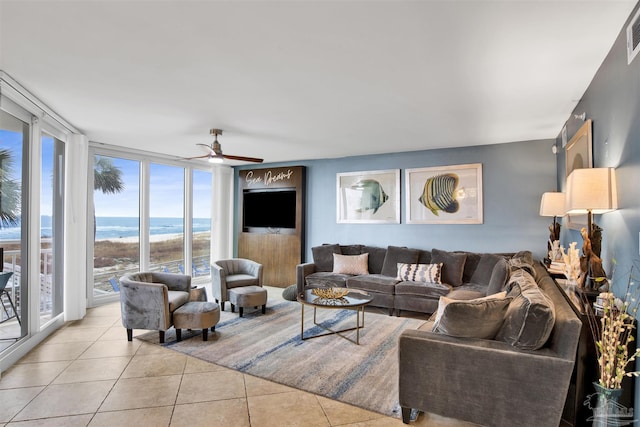 tiled living room with a water view, a wall of windows, and ceiling fan