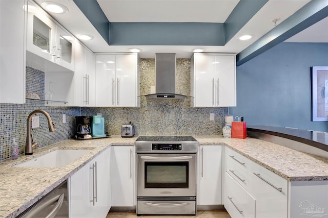 kitchen featuring sink, white cabinetry, stainless steel appliances, light stone countertops, and wall chimney range hood