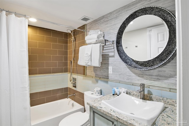 full bathroom featuring sink, tile walls, shower / tub combo, and toilet