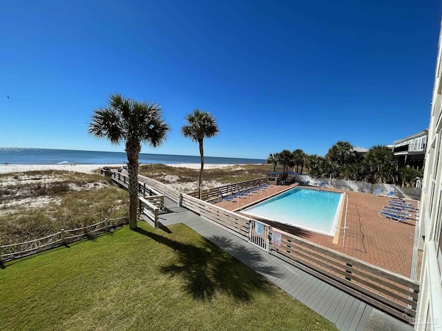 view of pool featuring a yard, a patio, a beach view, and a water view