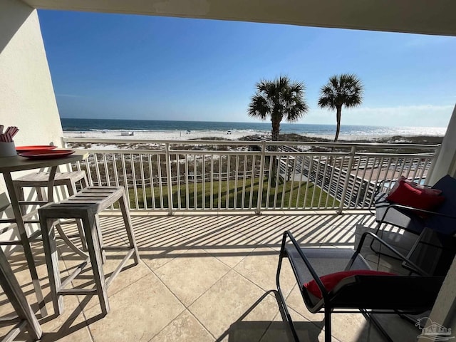 balcony with a water view and a view of the beach