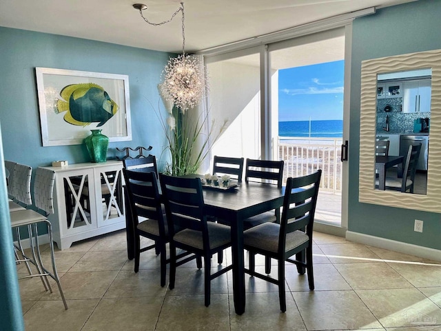 tiled dining space with a view of the beach, floor to ceiling windows, a chandelier, and a water view