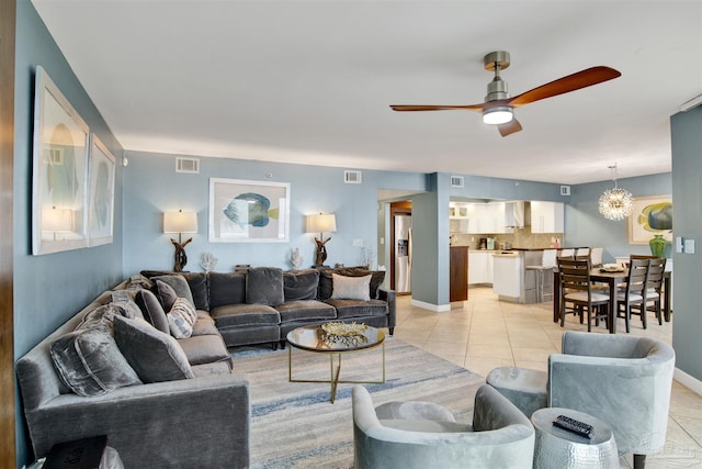 tiled living room with ceiling fan with notable chandelier