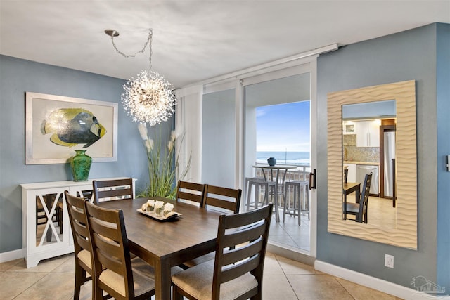 dining room featuring a water view, light tile patterned floors, and a notable chandelier