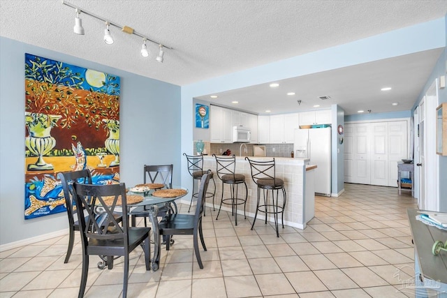 dining area with a textured ceiling and light tile patterned floors