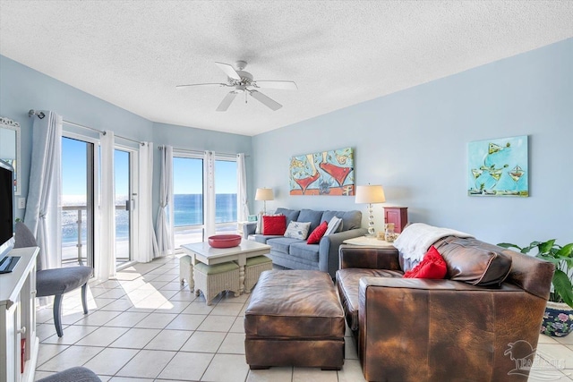 living room featuring a textured ceiling, light tile patterned flooring, a water view, and ceiling fan